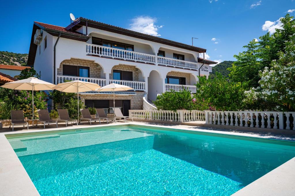 una villa con piscina frente a una casa en Apartments Villa Verica - Mit Meerblick & Pool auf der Insel Rab, en Banjol