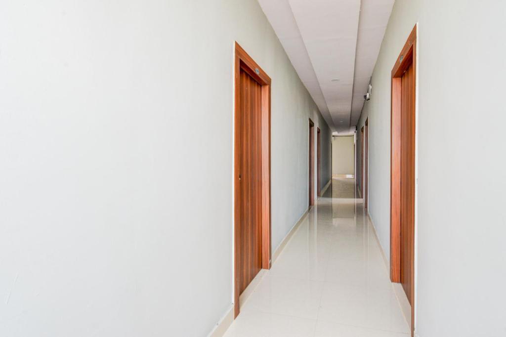 an empty corridor in a building with wooden doors at Hotel O SSR Grand in Surūrnagar