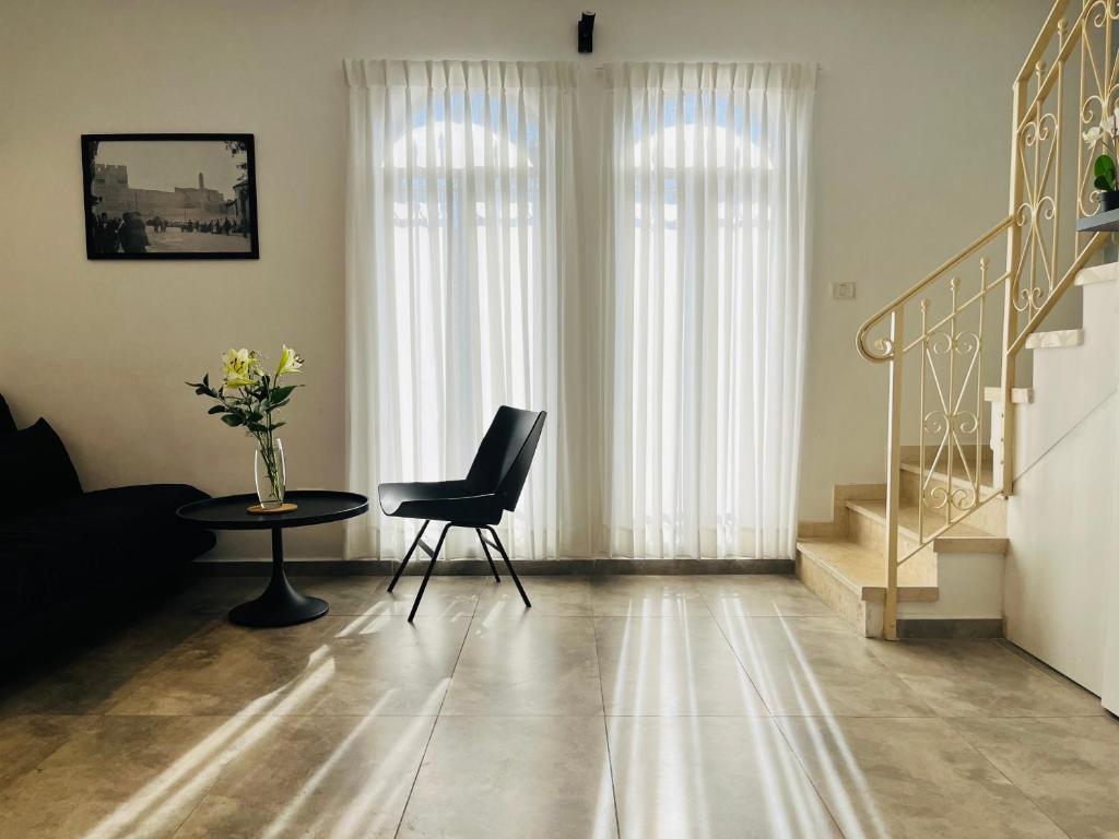 a living room with a chair and a table and stairs at Charming Kosher Private Duplex, Prime City Center, Steps to Machane Yehuda in Jerusalem
