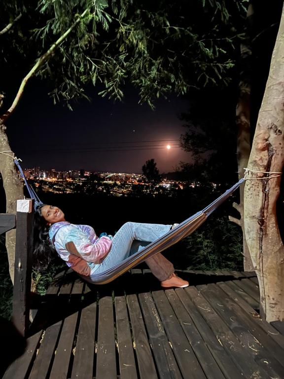a woman laying in a hammock in a tree at Domos Temuco, Cumbres del Conunhuenu in Temuco