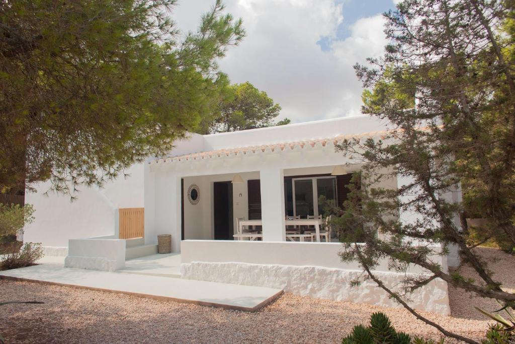 a white house with trees in front of it at Casa immersa nel verde a pochi passi dalla playa in Illes Balears