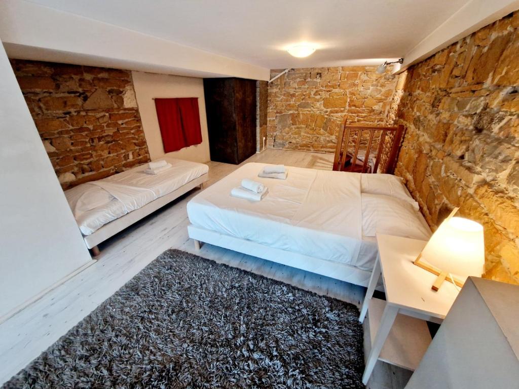 2 Betten in einem Zimmer mit einer Steinmauer in der Unterkunft Duplex central à Lyon pour 5 personnes in Lyon