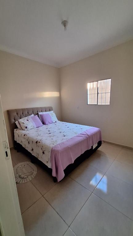 a bedroom with a large bed with pink pillows at Casa temporada Martins,RN in Martins