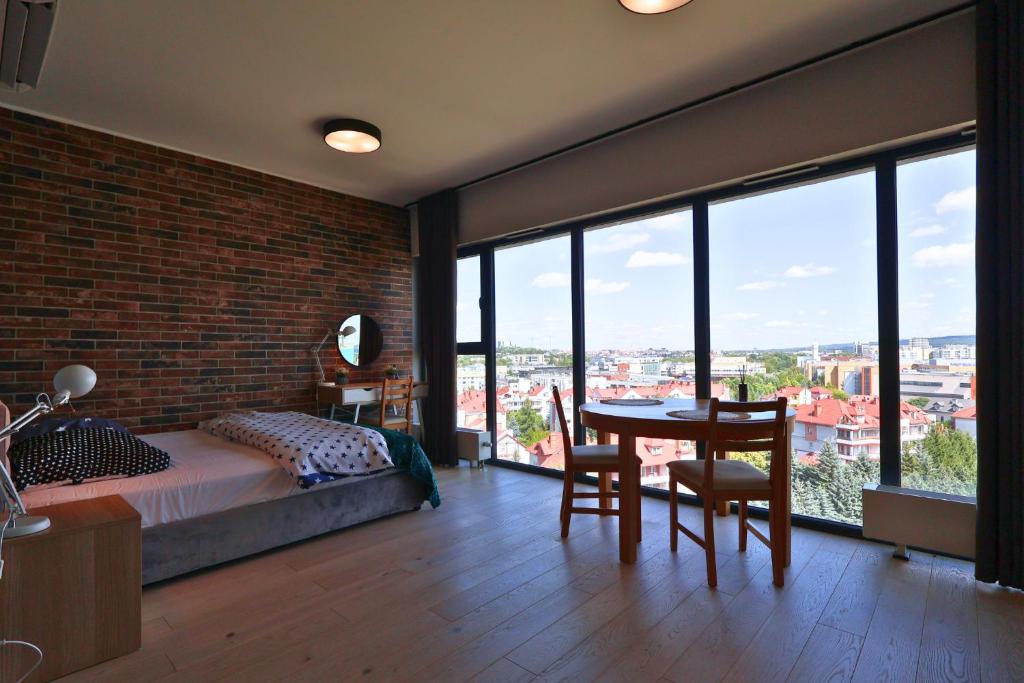 une chambre avec un mur de briques, un lit et une table dans l'établissement Apartament #CapitalTower 167 FV PARKING, à Rzeszów