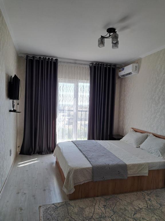 una camera da letto con un letto e una grande finestra di Жана кала 1 комнатная квартира a Türkistan