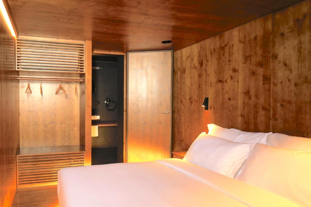 1 dormitorio con cama blanca y paredes de madera en Zero Box Lodge Coimbra, en Coímbra