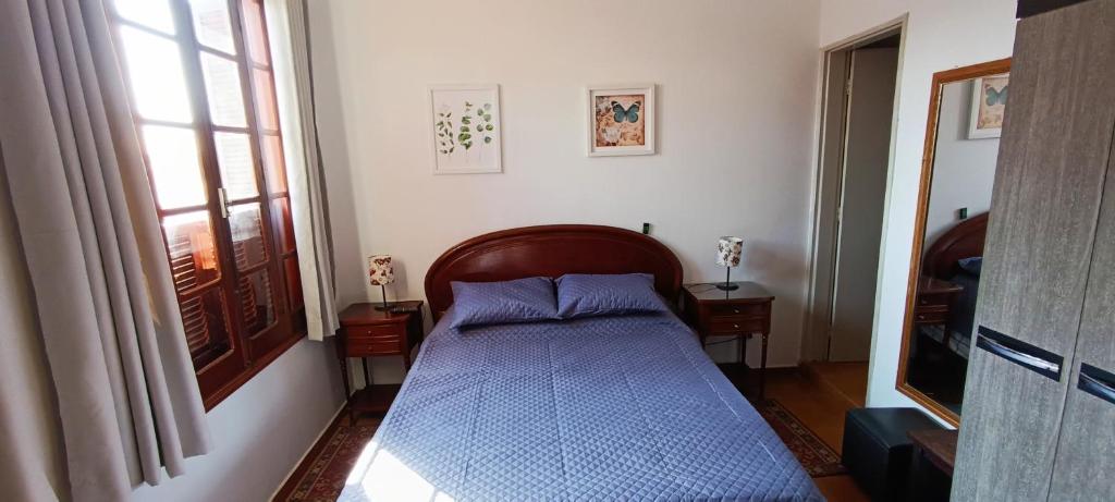 a bedroom with a bed with a blue comforter and a window at Casa Rosário Centro de Amparo in Amparo