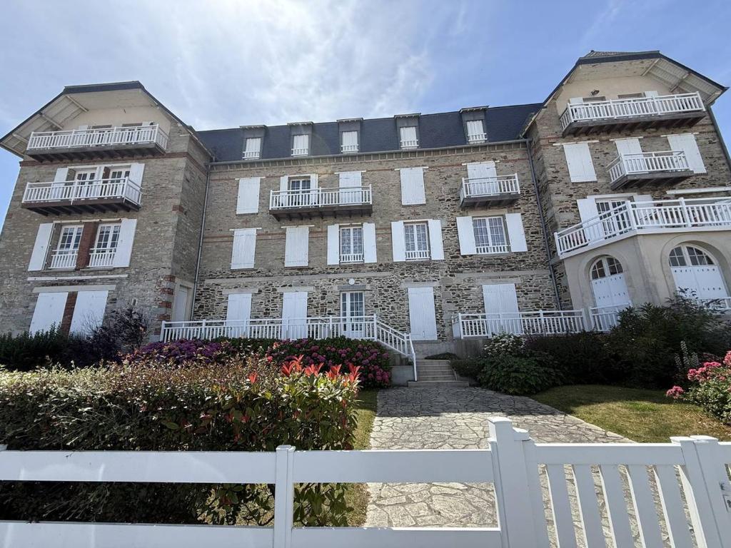 een groot gebouw met een wit hek ervoor bij Appartement Quartier des Mielles Vue mer in LʼIsle-Saint-Cast