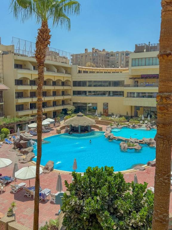 a view of a hotel with a pool and palm trees at Amarante Pyramids Hotel in Cairo