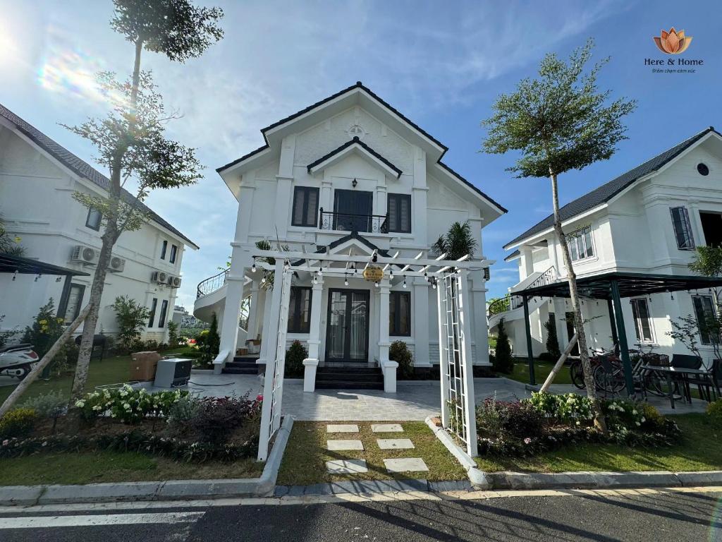 a white house with an arch in front of it at Here & Home Villa Vườn Vua in Kon Rung (1)