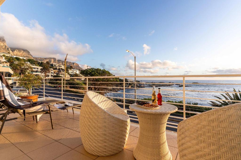 a balcony with chairs and a table with a view of the ocean at Sunset Azure Studio - Pool Views 2 min to beach in Cape Town