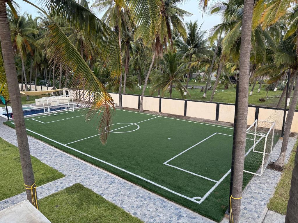 a tennis court with palm trees in a resort at Rancho El Valle in Acajutla