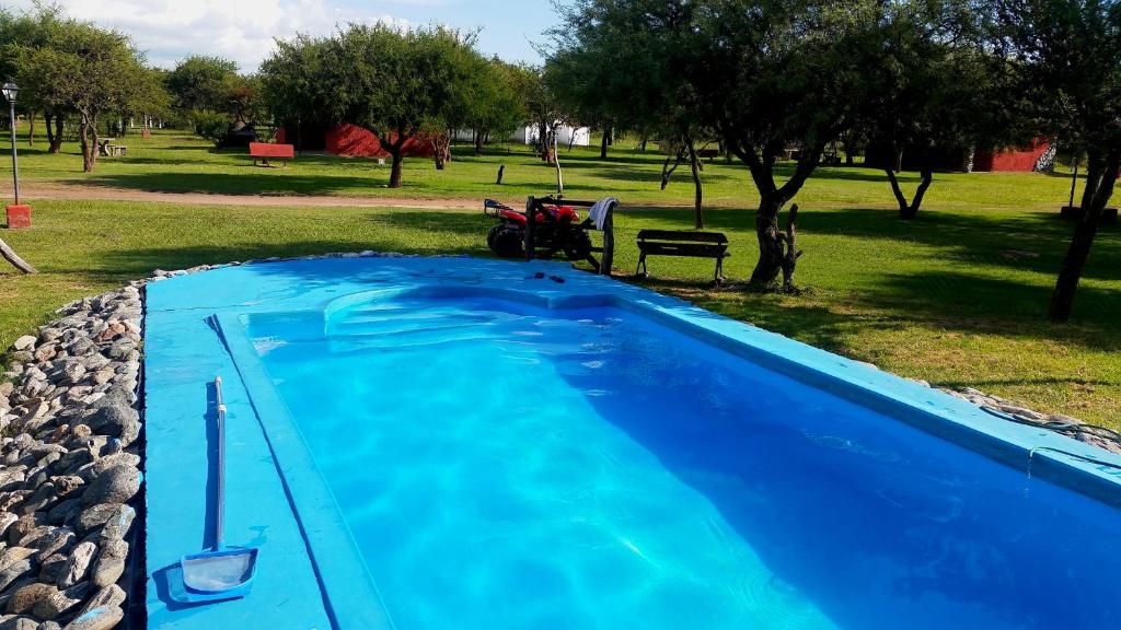 Cabañas Calma Chicha في كورتاديراس: حمام سباحة أزرق مع دراجة نارية متوقفة في حديقة