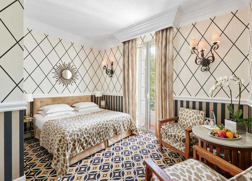 a hotel room with a bed and a table at Hôtel Belles Rives in Juan-les-Pins