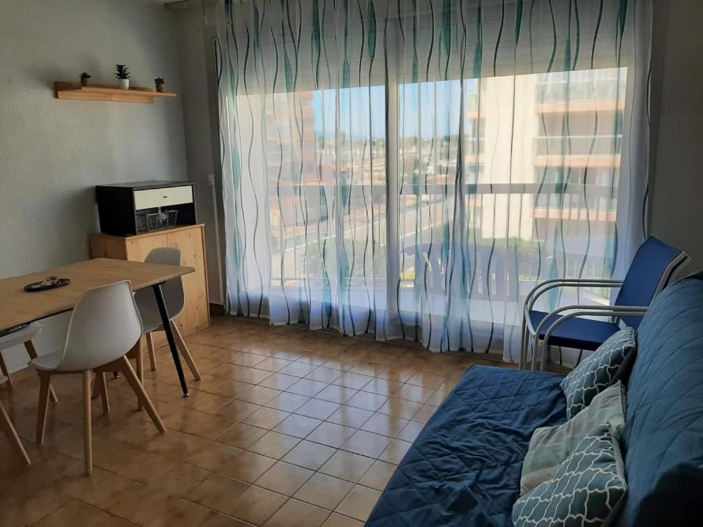 a living room with a bed and a table and a window at PORT et PLAGE in Le Barcarès