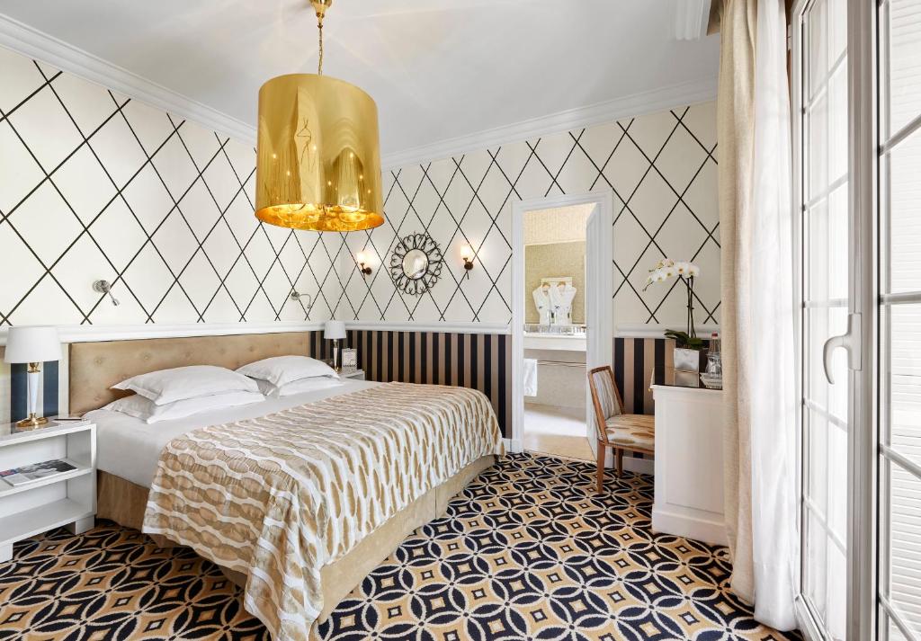 a bedroom with a bed and a chandelier at Hôtel Belles Rives in Juan-les-Pins