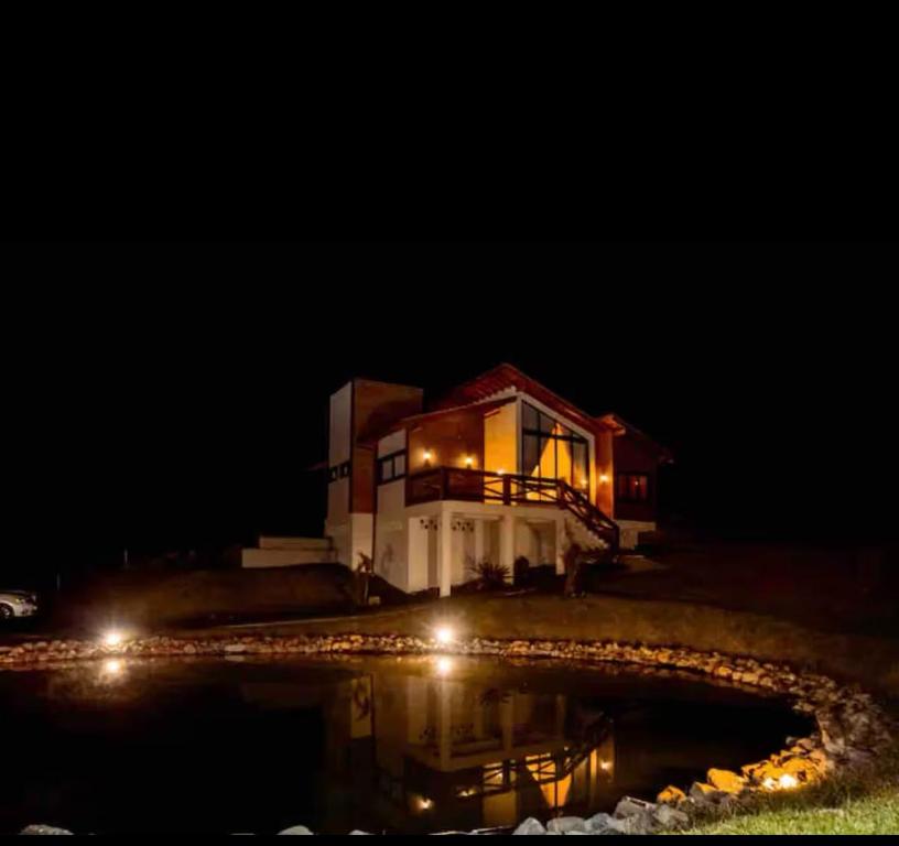 una casa por la noche con un reflejo en el agua en Casa do Vinho no Altos da Serra, en Bom Jardim da Serra