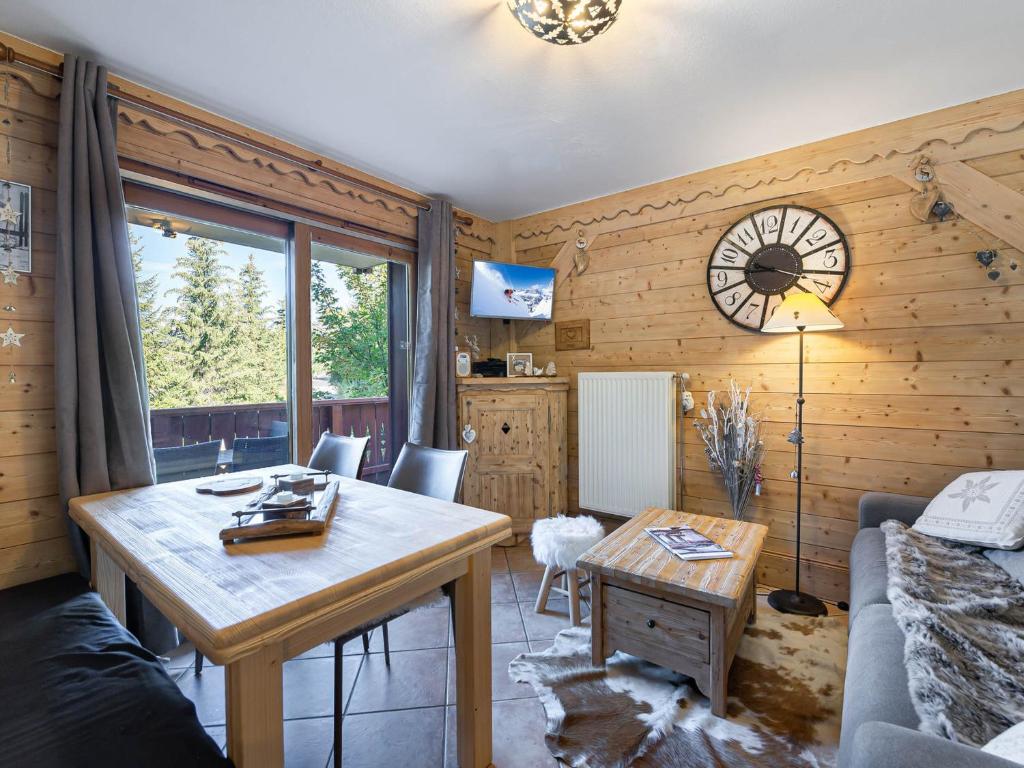 - un salon avec une table et une horloge murale dans l'établissement Appartement cosy avec piscine, spa et parking, au pied des pistes, 4 pers., Méribel Village. - FR-1-566-29, à Les Allues