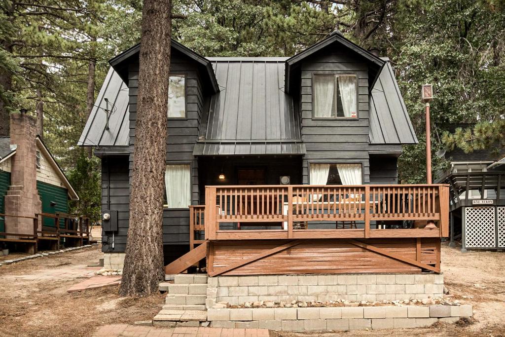 a black house with a porch and a tree at Pineland Getaway - Serene Escape in Green Valley Lake