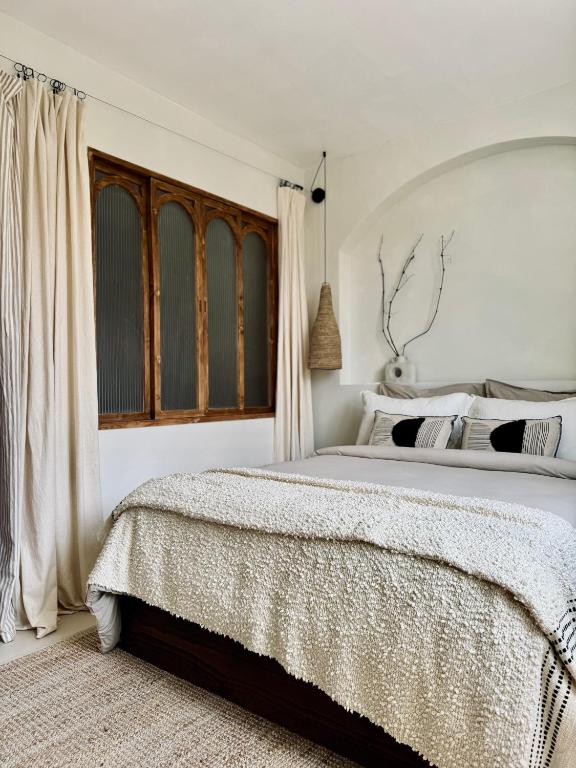 a white bedroom with a large bed and a window at VINEÀ Suite in Angé