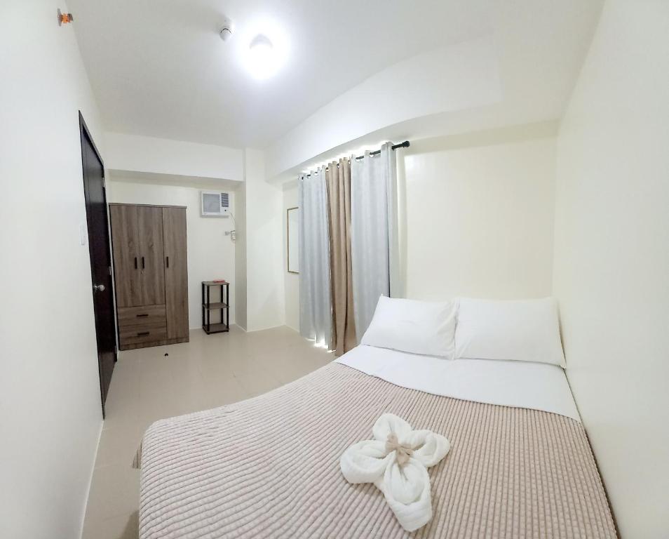 a bedroom with a white bed with a bow on it at Cozy Nook in the City in Manila