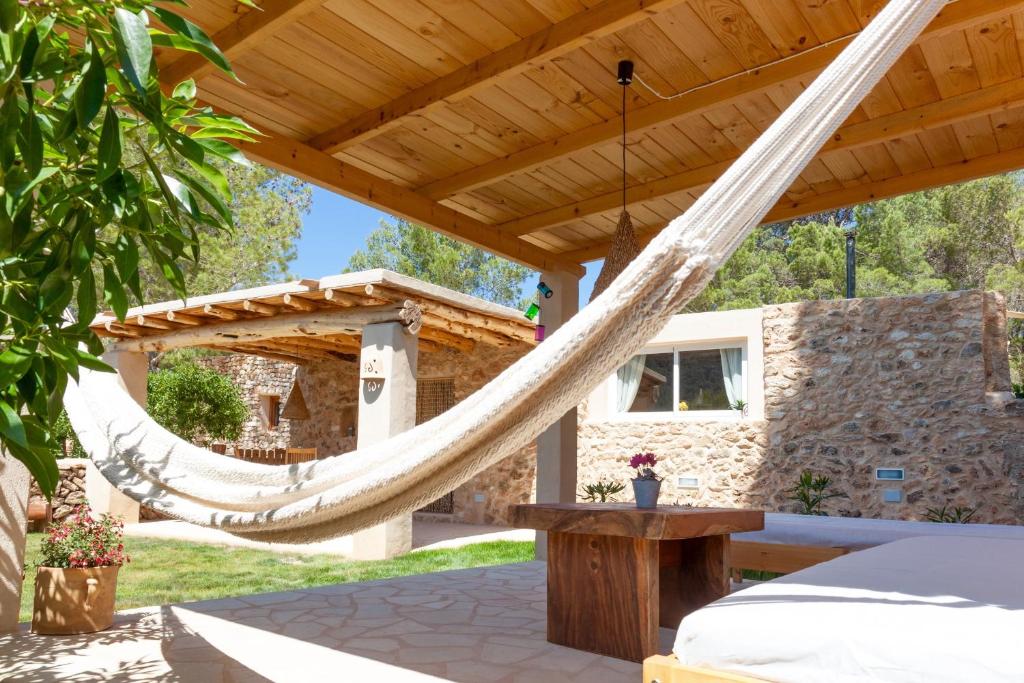 a patio with a hammock under a wooden pergola at Villa Es Coral in Cala Vadella