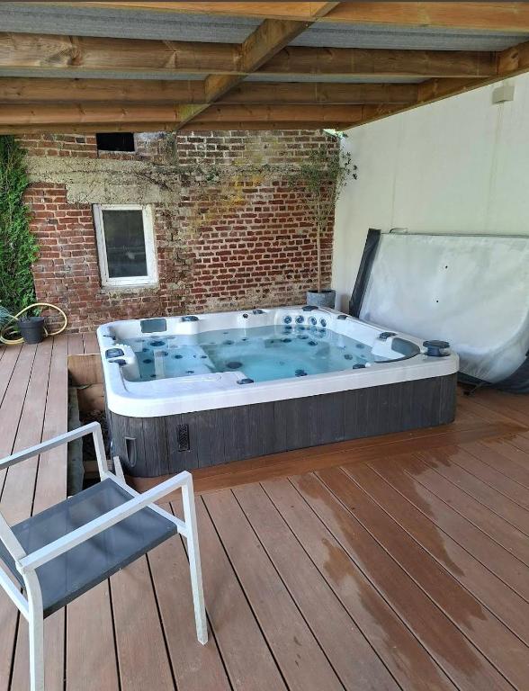 a large hot tub on a deck with a chair at La C-onciergerie in Camblain-lʼAbbé