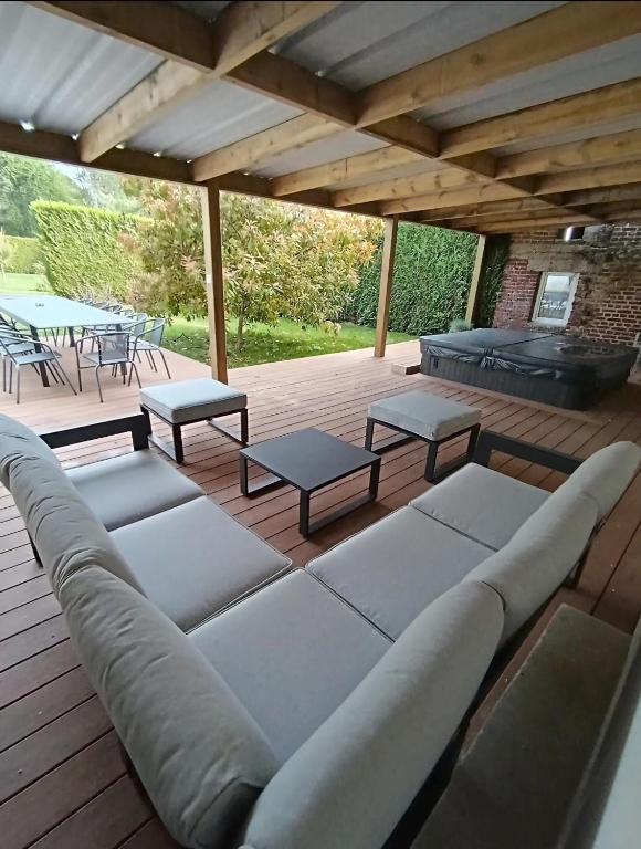 une terrasse avec un canapé, des tables et un grill dans l'établissement La C-onciergerie, à Camblain-lʼAbbé