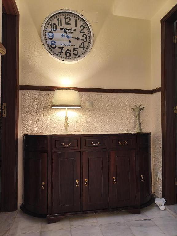 a clock on the wall above a wooden cabinet at Casa da Praça I in Amoreira