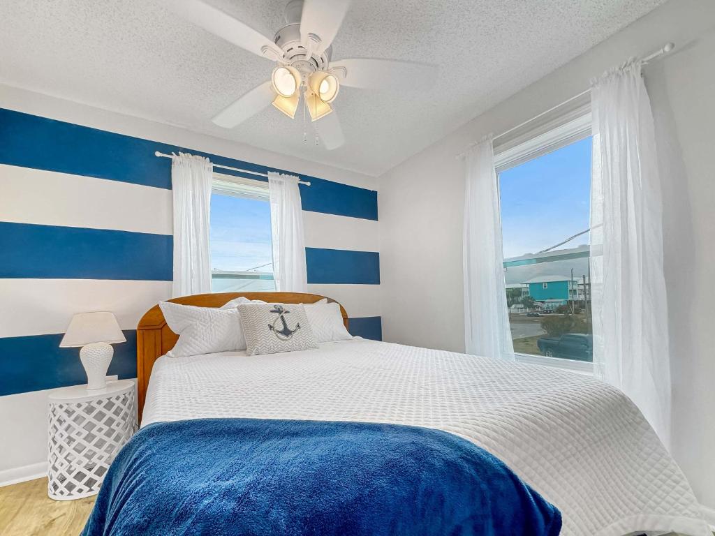 ein blau-weißes Schlafzimmer mit einem Bett und einem Fenster in der Unterkunft Bungalow by the Bay with FREE ACTIVITIES in Gulf Shores