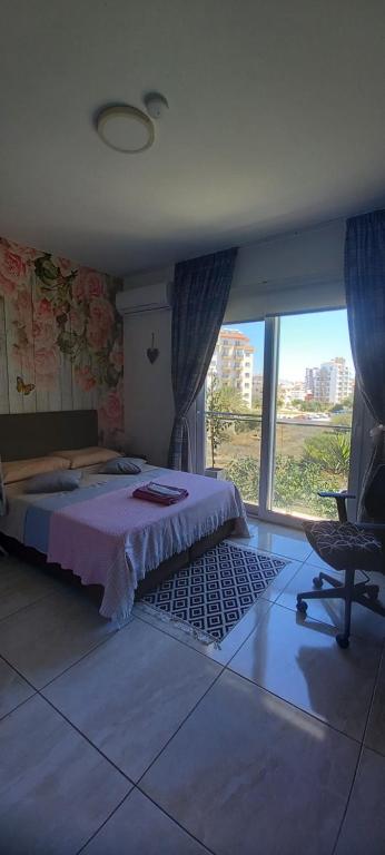 a bedroom with a bed and a chair and a window at Studio LUX in Mağusa
