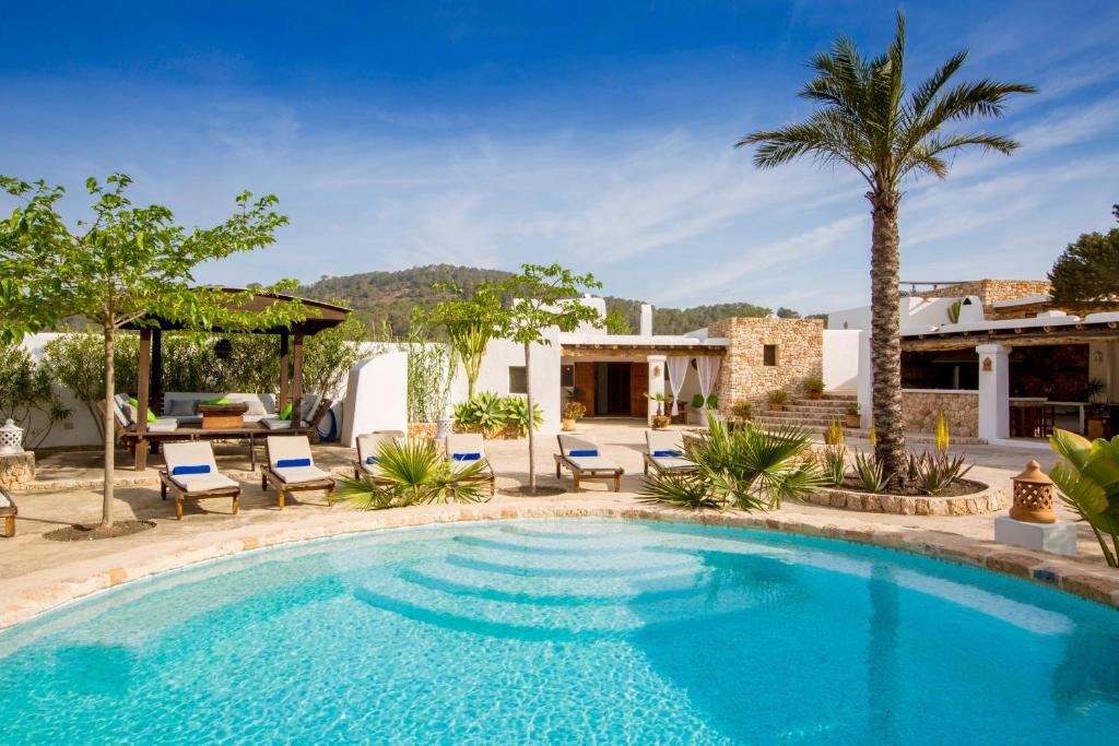 a swimming pool in a yard with chairs and a house at Villa Sa Paissa in Cala Vadella