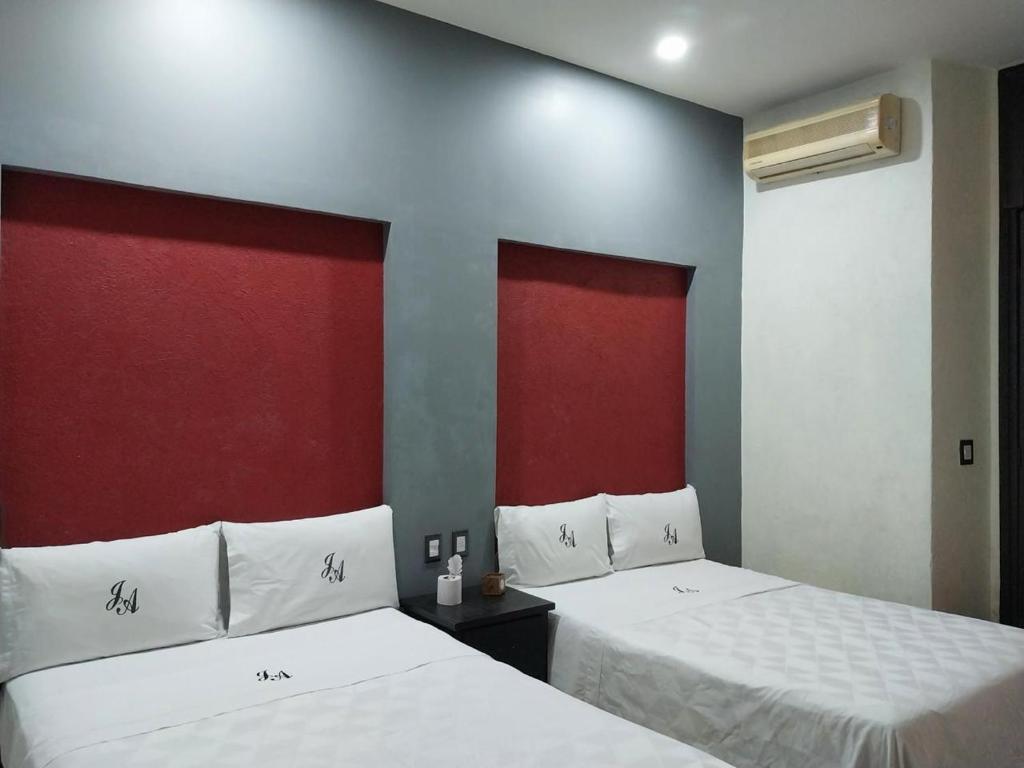 Dos camas en una habitación con rojo y blanco. en Hotel JA CENTRO Guadalajara, en Guadalajara