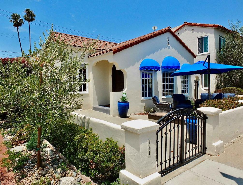 a white house with blue umbrellas in front of it at Belmont Shore Beach House - Incredible Oceanfront Views in Long Beach