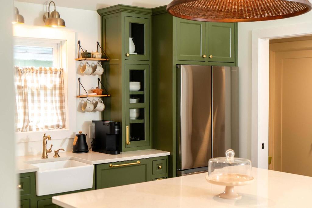 a kitchen with green cabinets and a stainless steel refrigerator at Magnolia Manor - Remodeled Home Near Downtown in Lake Geneva