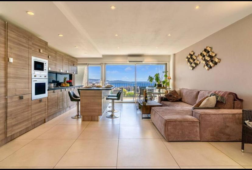 un salon avec un canapé et une table et une cuisine dans l'établissement Magnificent 3 Rooms-Sea View-Terrace-Pool, à Nice
