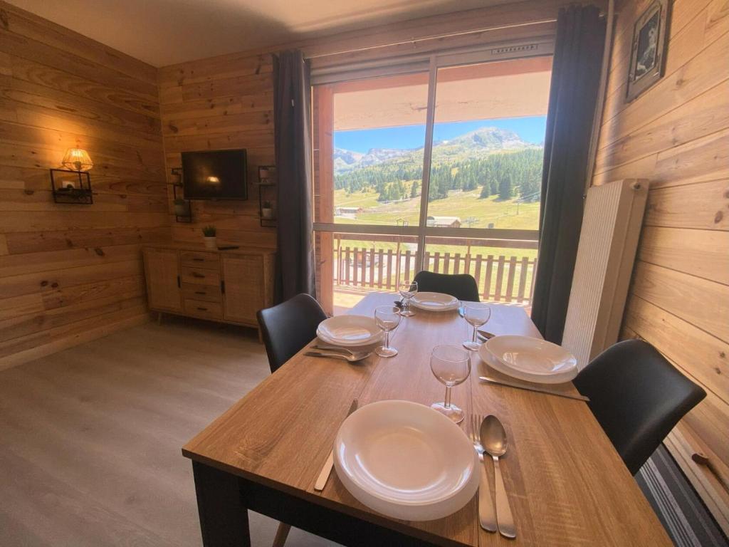 a wooden table with plates and wine glasses on it at Résidence Le Bois D'aurouze - Studio pour 4 Personnes MAE-8684 in Le Dévoluy