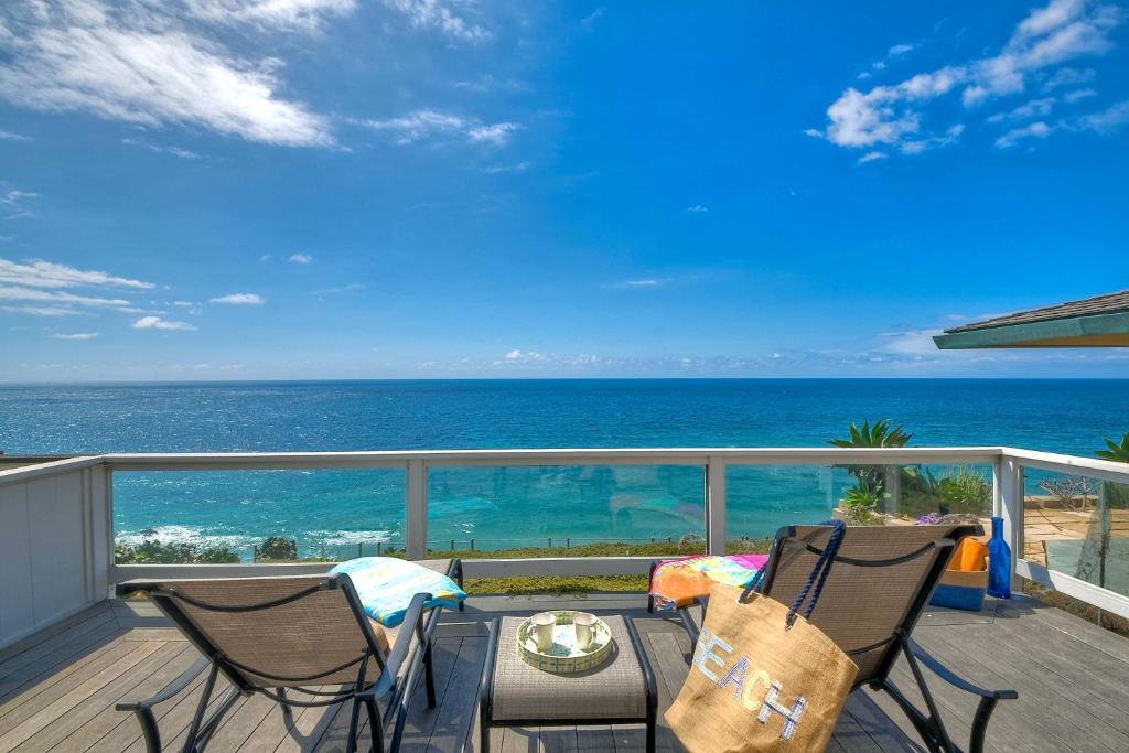 a balcony with a table and chairs and the ocean at Beachfront Sunset in Encinitas