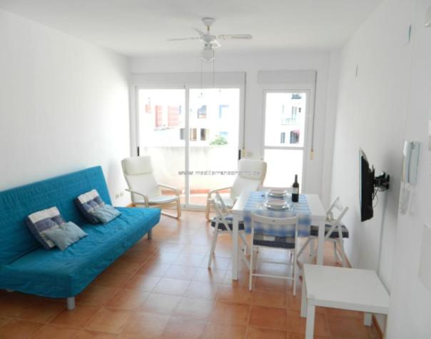 a living room with a blue couch and a glass table at Piso Playa de Canet in Canet de Berenguer