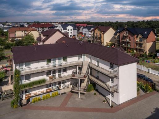 a large white building with a black roof in a city at Apartamenty Afrodyta in Karwia