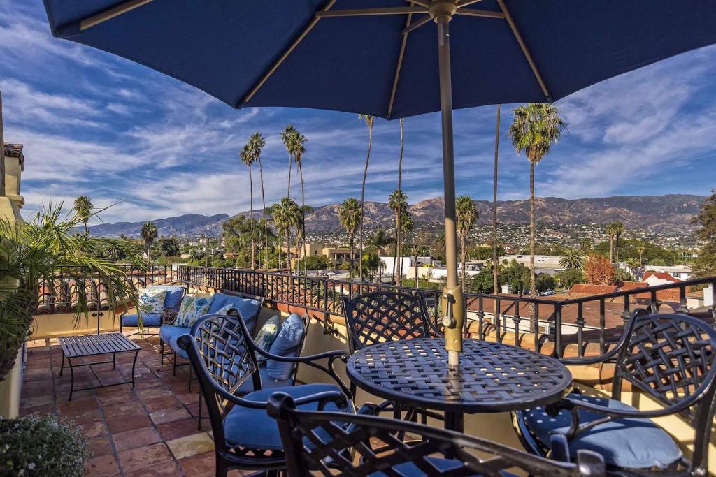 a patio with tables and chairs and an umbrella at Luxurious Mykonos in Santa Barbara with Outdoor Deck Short Bike Ride to Beach in Santa Barbara