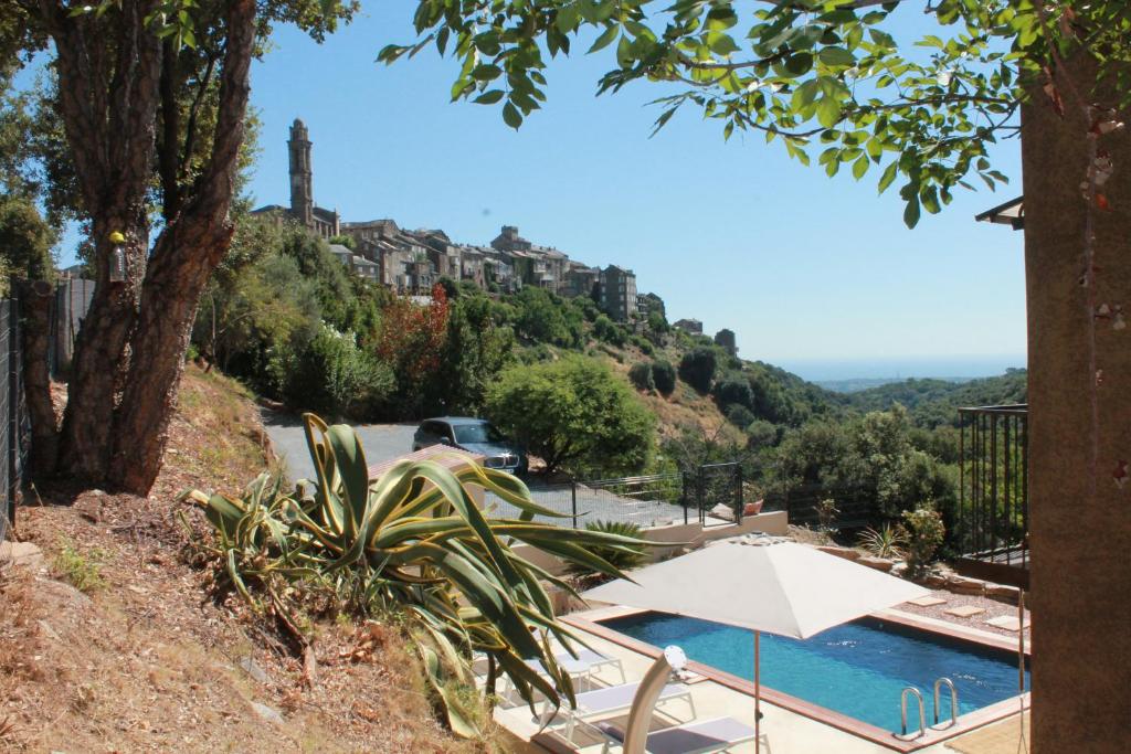 een zwembad met een parasol en een gebouw op een heuvel bij La Casuccia in Venzolasca
