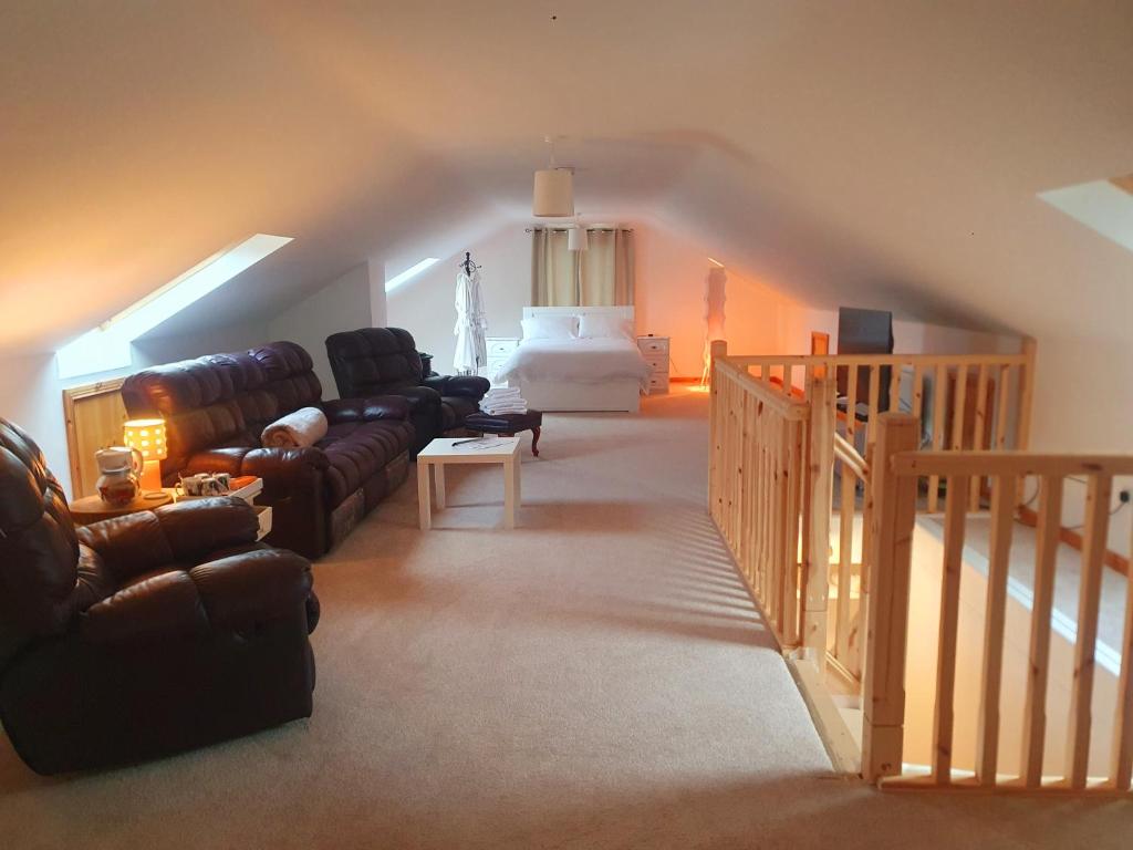 a living room with leather couches and a staircase at Urkers' Guest Accommodation in Crossmaglen