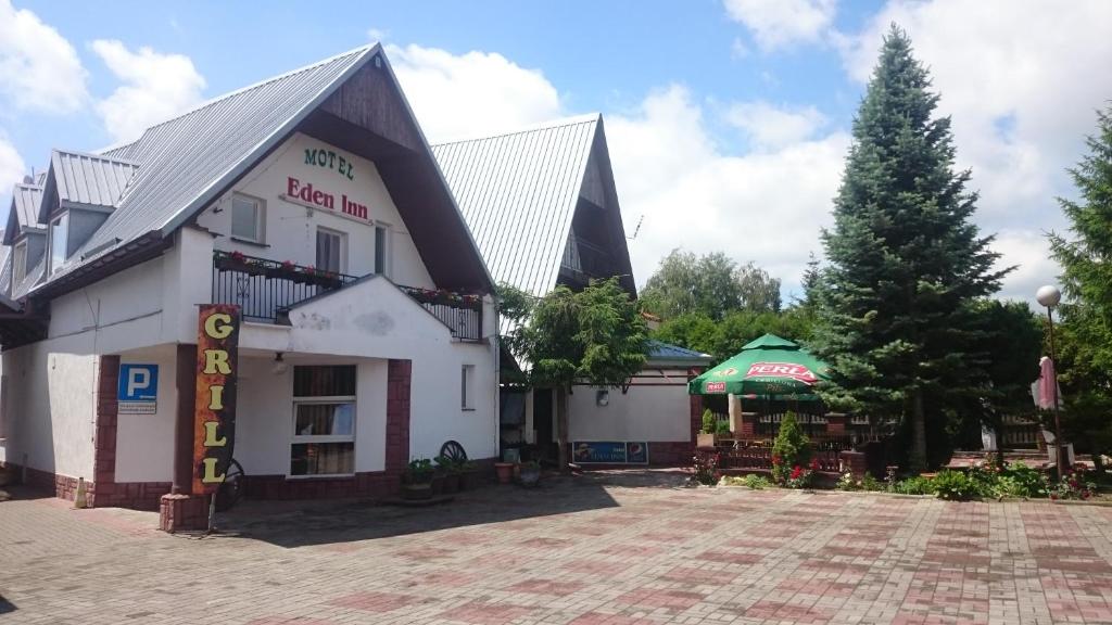 a large white building with a tree in front of it at Motel Eden in Zamość