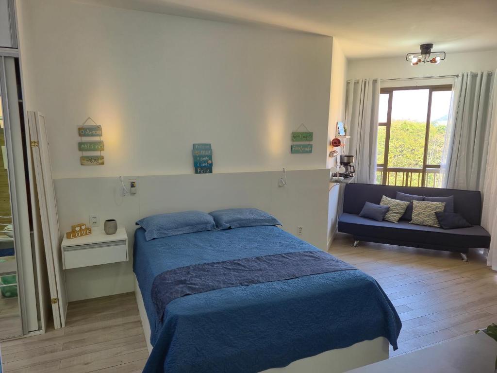 a bedroom with a blue bed and a couch at Loft Melhor do Sahy - Magaratiba RJ in Mangaratiba