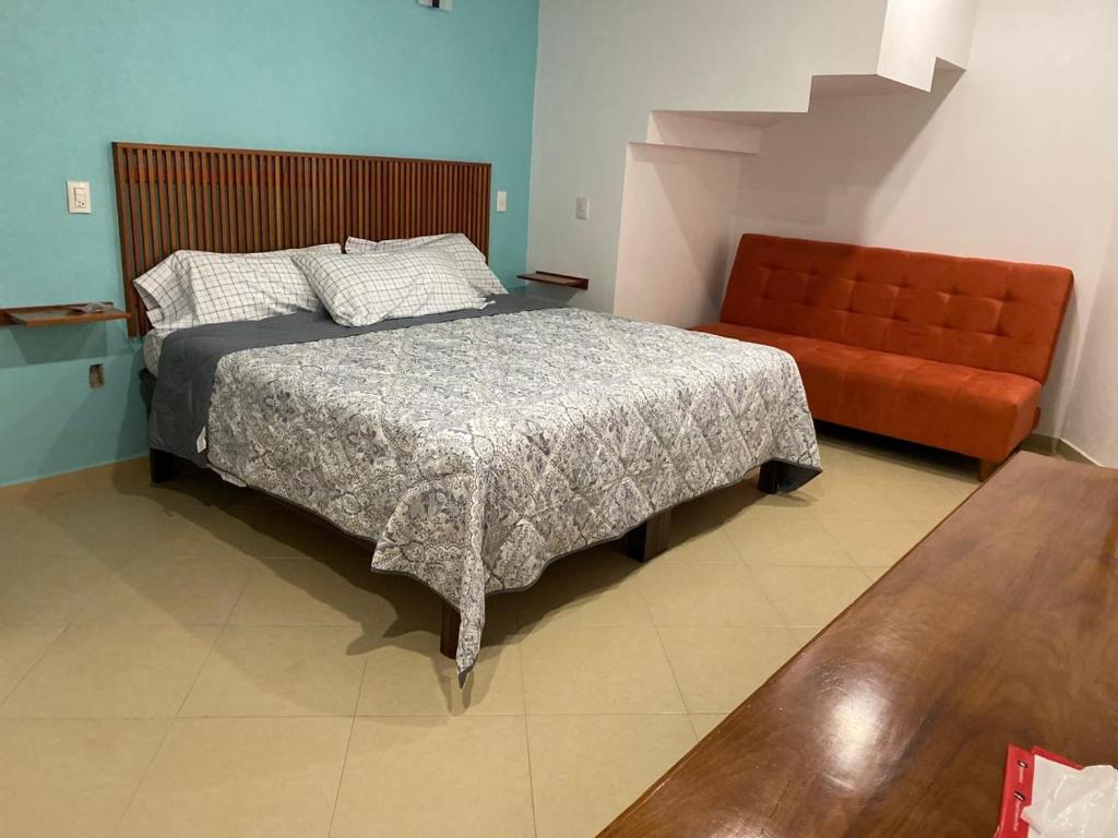 a bedroom with a bed and an orange couch at La Casa de los Abuelos in Zacatlán