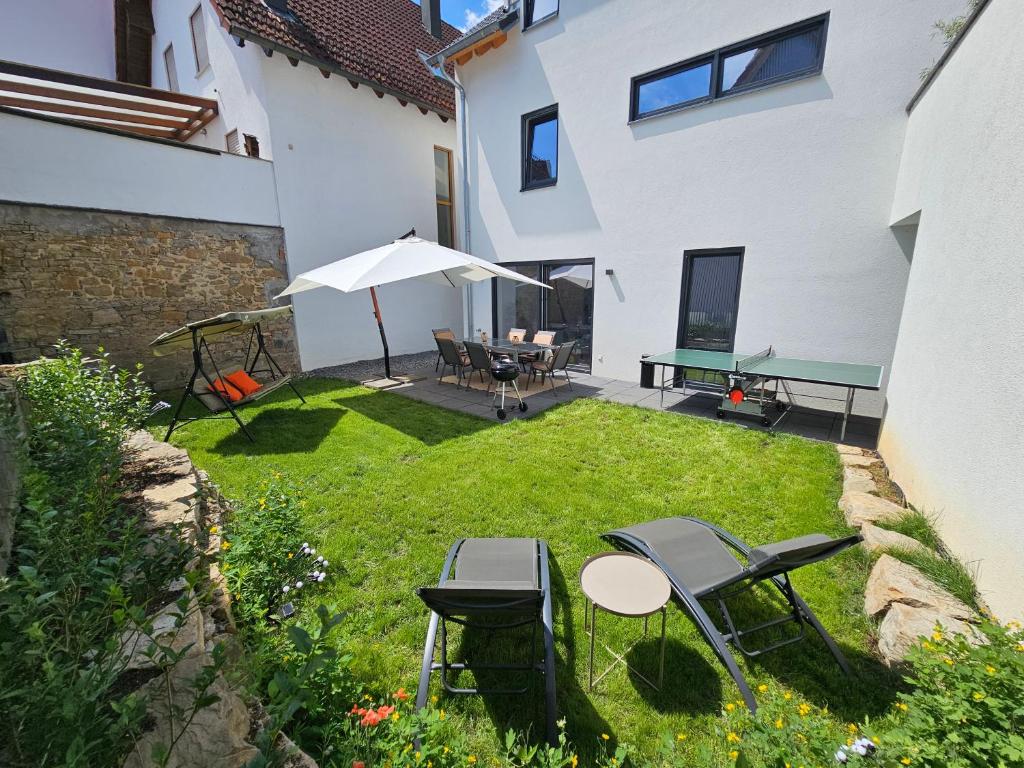 a backyard with chairs and tables and an umbrella at Hygge Home - mit Garten und Stellplatz für Feriengäste-, Monteure / Netflix / 10 min. zur Sinsheim Therme und zur Autobahn in Sinsheim
