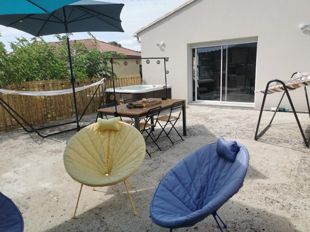 une terrasse avec 2 chaises et une table avec un parasol dans l'établissement 50m2, 4 personnes , jacuzzi et sauna privatif, à Piolenc