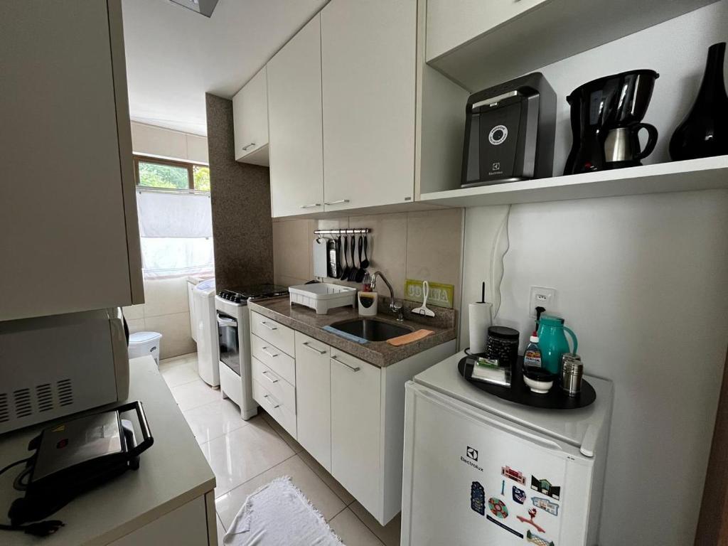 una cucina con mobili bianchi, un lavello e un microonde di Apartamento Graças 108 a Recife