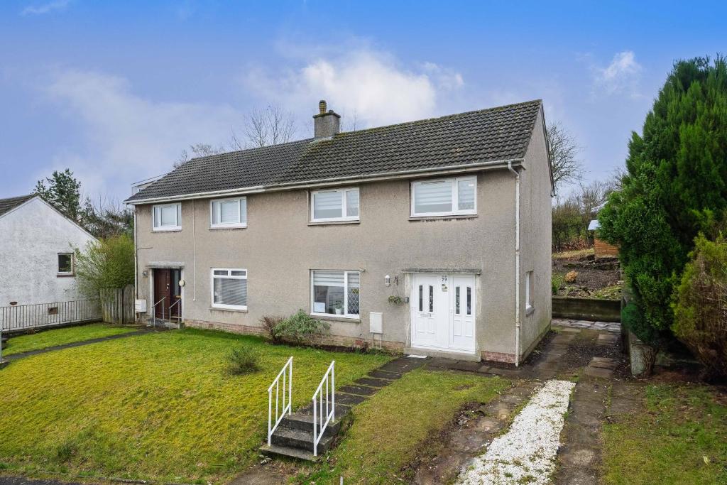 a large white house with a yard and a house at Comfortable & cozy Home Stay in East Kilbride